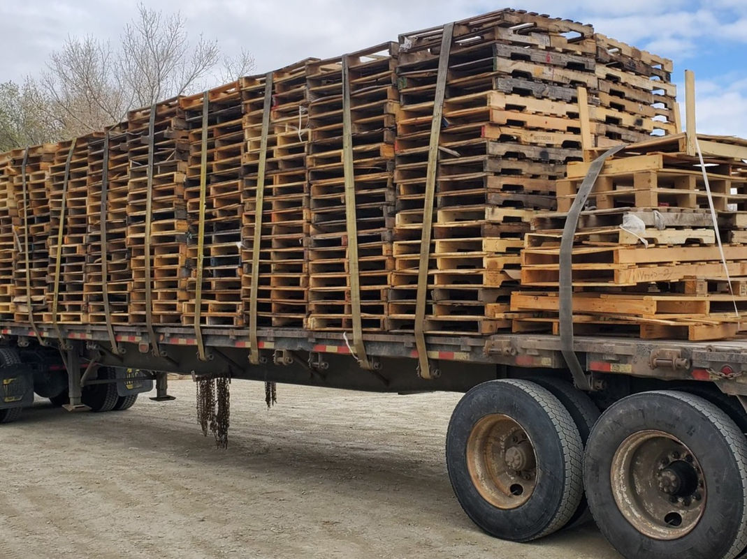 Smith Pallets flatbed truck loaded with stacked recycled pallets, ready to leave the yard